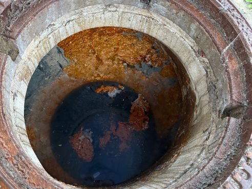 Ein verstopfter Kanal, Schacht mit offenem Deckel